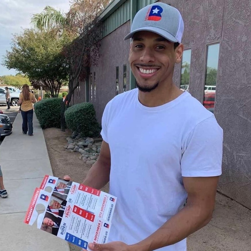 Man holding Bienvenido voter guides outdoors